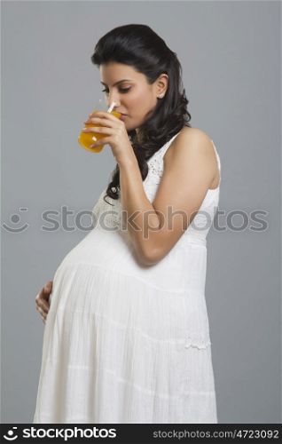 Pregnant woman drinking a glass of orange juice
