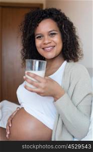 Pregnant woman drinking milk in bedroom