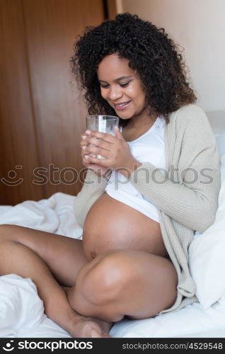 Pregnant woman drinking milk in bedroom