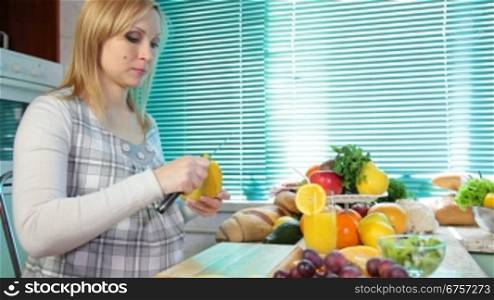 Pregnant woman eating a banana in the kitchen