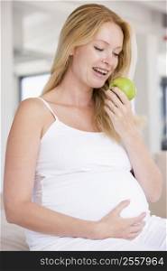 Pregnant woman eating apple and smiling