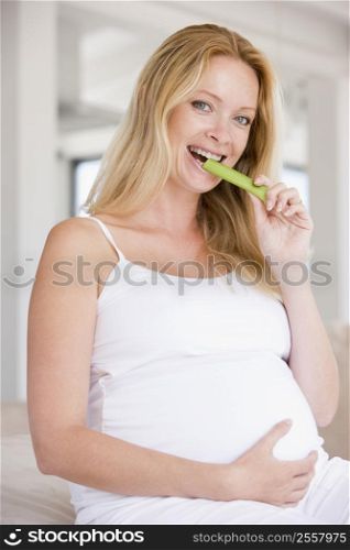 Pregnant woman eating celery and smiling