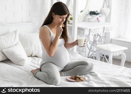 pregnant woman eating chocolate cookies drinking milk