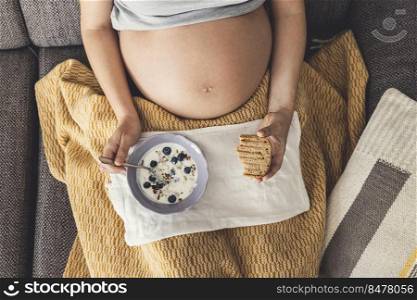 Pregnant woman eating healthy food at home