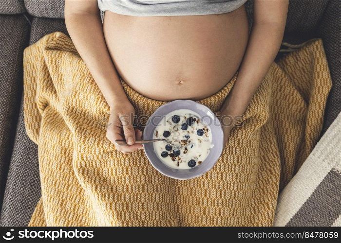Pregnant woman eating healthy food at home