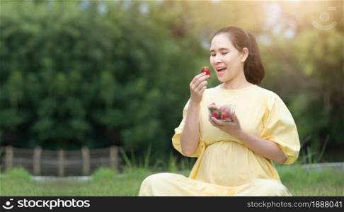 Pregnant woman eating strawberry resting outdoor