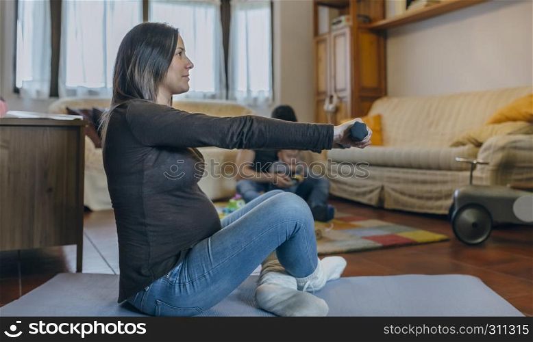 Pregnant woman exercising in the living room of her house. Pregnant woman exercising in the living room