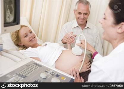 Pregnant woman getting ultrasound from doctor with husband watching