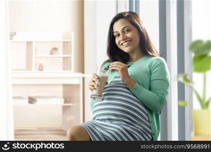 Pregnant woman having a glass of chocolate milk at home. 