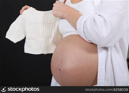Pregnant woman holding a baby&acute;s jumper