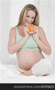 Pregnant woman holding a clock