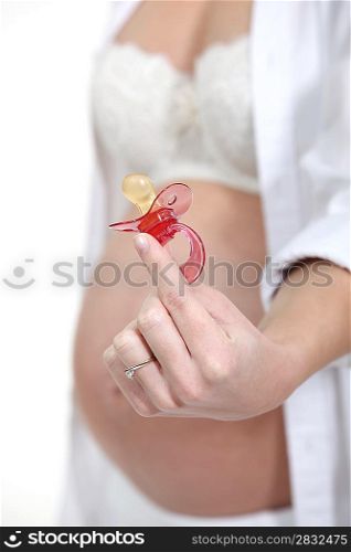 pregnant woman holding a pacifier