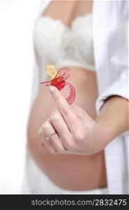pregnant woman holding a pacifier