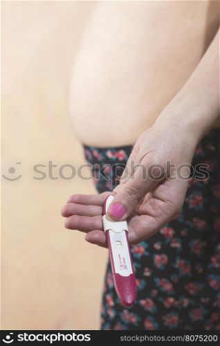 Pregnant woman holding a pregnancy test. Close up