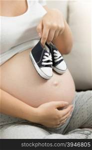 Pregnant woman holding baby boy shoes on belly