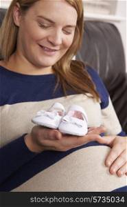 Pregnant Woman Holding Baby Shoes