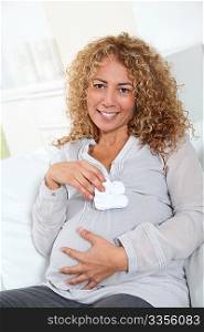 Pregnant woman holding baby slippers