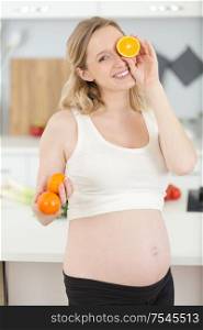 pregnant woman holding glass of orange juice and orange