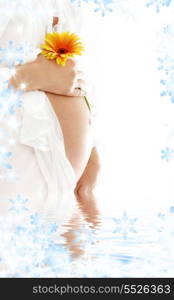 pregnant woman holding her belly and yellow flower in water