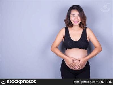 Pregnant Woman holding her hands in a heart shape on her belly