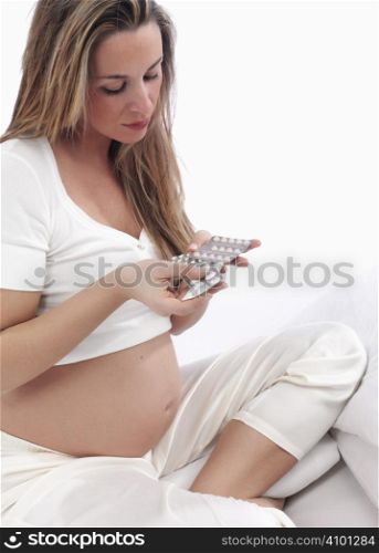 Pregnant woman holding medicine on a white background