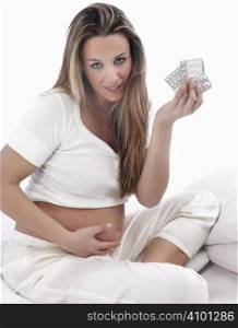 Pregnant woman holding medicine on a white background