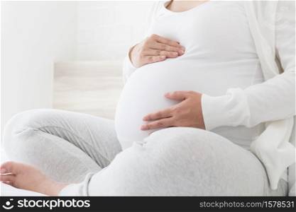 Pregnant woman holds her hands on her swollen belly on white bed, Love and feel joyful as emotional well affect to baby neurological and psychological development