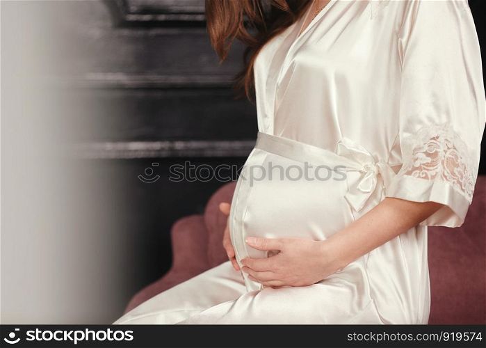 pregnant woman in a beautiful dress. Focus on the abdomen.