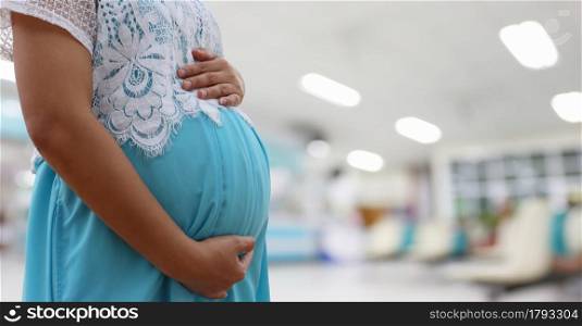 Pregnant woman in a blue dress on hospital blurred background and have copy space.