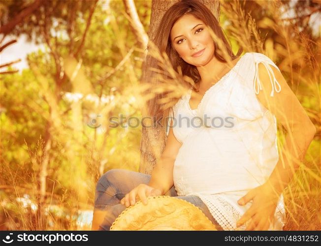 Pregnant woman in autumn park, beautiful expectant female relaxing outdoors in sunny autumnal day, happy and healthy pregnancy concept