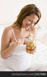 Pregnant woman in bed eating pickled eggs smiling