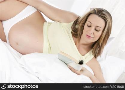 Pregnant woman in bedroom reading book
