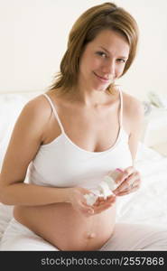 Pregnant woman in bedroom with medicine smiling