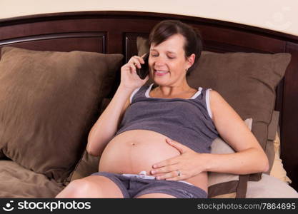 Pregnant woman in her bed talking on her smart phone