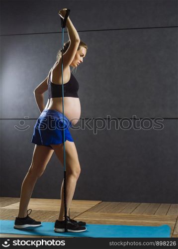 Pregnant woman in her thirties exercising with a resistance band.