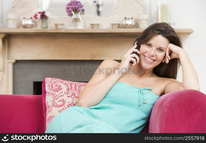 Pregnant woman in living room talking on telephone and smiling