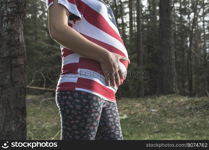 Pregnant woman in the forest. American national flag shirt