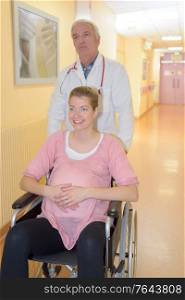pregnant woman in wheelchair with doctor in the hospital corridor