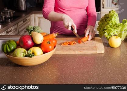Pregnant woman is cooking dishes in the kitchen. Pregnant woman is cooking