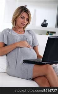 Pregnant woman looking at a laptop computer