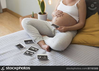 Pregnant woman looking to the picture of the ultrasound, Prenatal health care concept.