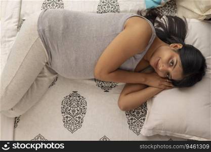Pregnant woman lying down on bed at home
