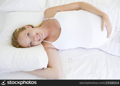 Pregnant woman lying in bed smiling