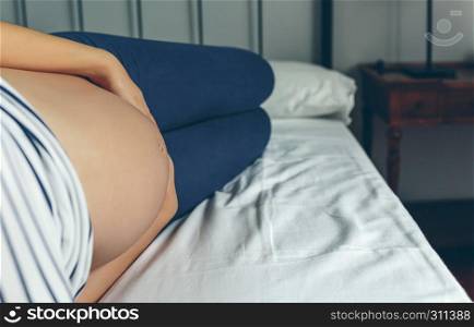 Pregnant woman lying in bed touching her belly. Pregnant lying touching her belly
