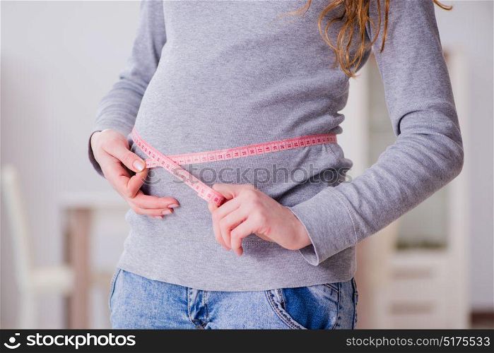 Pregnant woman measuring belly with centimeter