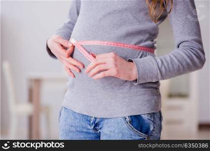 Pregnant woman measuring belly with centimeter