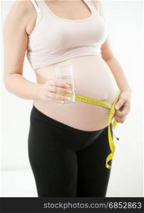 Pregnant woman measuring belly with measuring tape