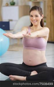pregnant woman meditates indoor in yoga pose