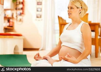 Pregnant woman meditating doing pregnancy yoga sitting on the floor in her home