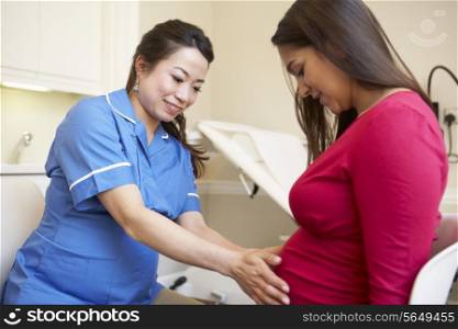 Pregnant Woman Meeting With Nurse In Clinic